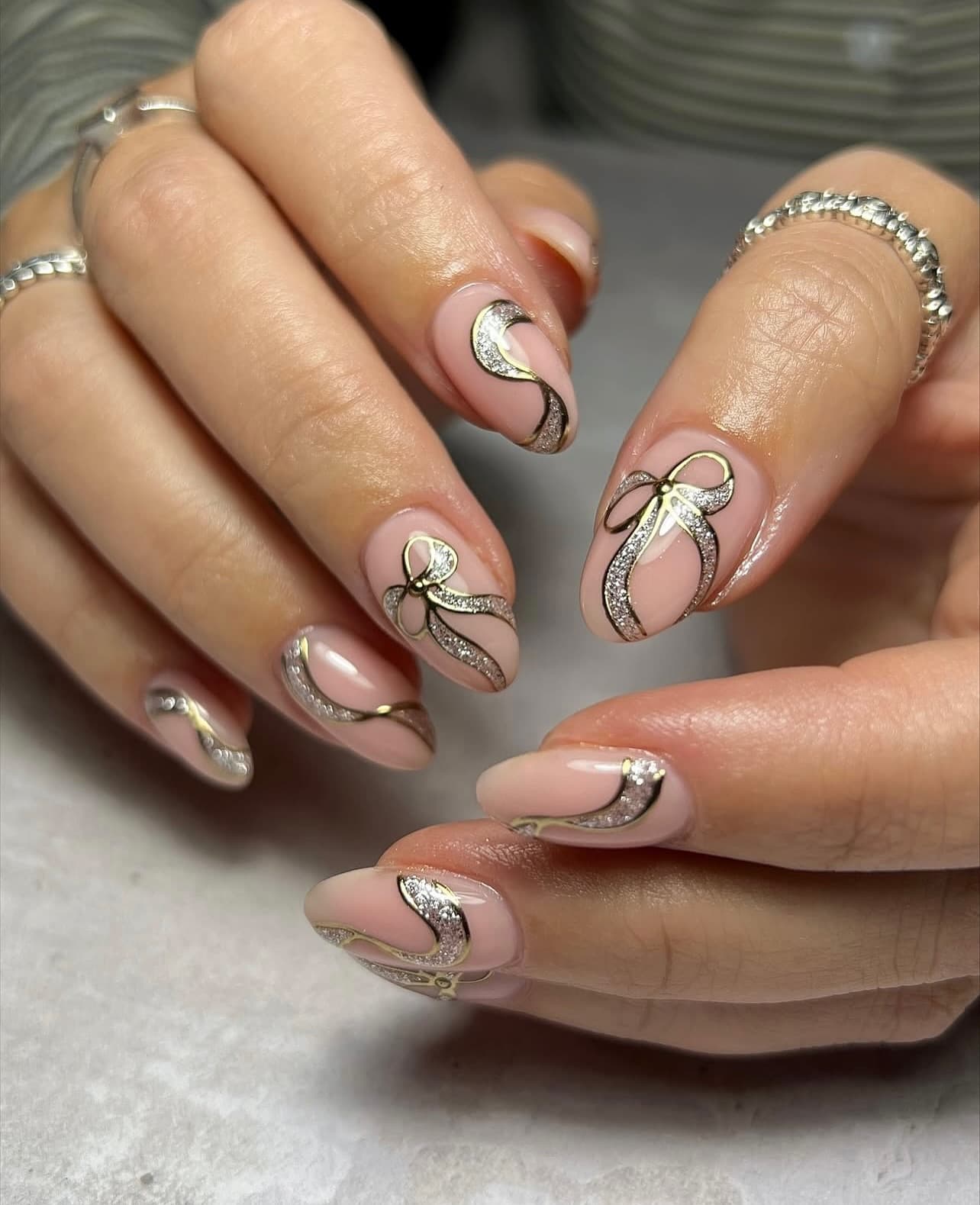 Nude gel nails with gold and silver glitter bow nail art