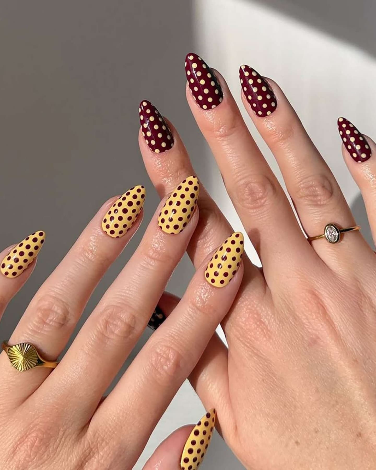 Yellow and burgundy polka-dot nail art on both hands