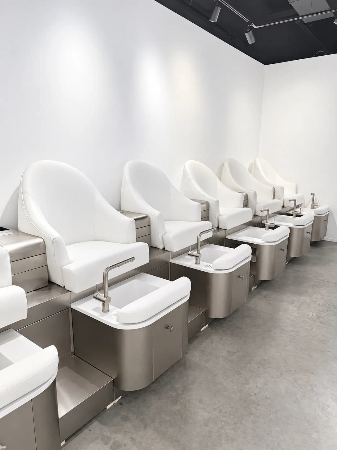 Row of white pedicure chairs and foot basins in the Tomy Rivero Beauty Cafe studio